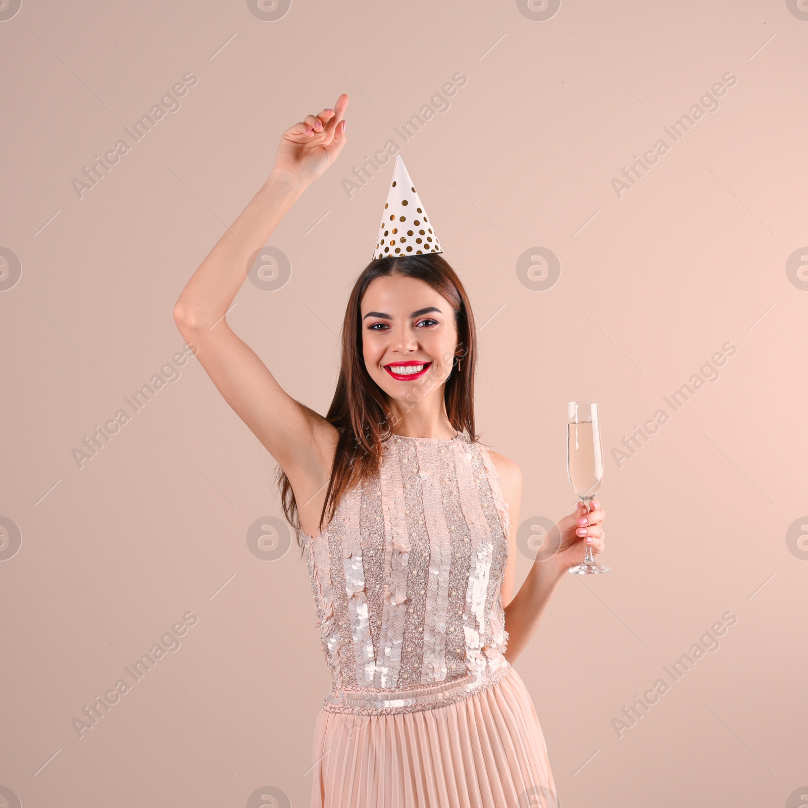 Photo of Portrait of happy woman with party hat and champagne in glass on color background