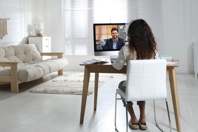 Image of African American woman with headphones and computer at online lesson, back view. E-learning