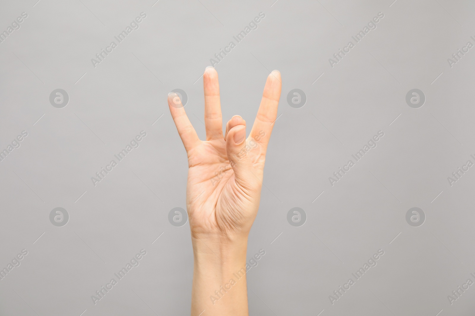 Photo of Woman showing number eight on grey background, closeup. Sign language