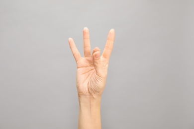 Photo of Woman showing number eight on grey background, closeup. Sign language