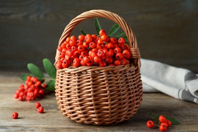 Photo of Fresh ripe rowan berries with green leaves on wooden table