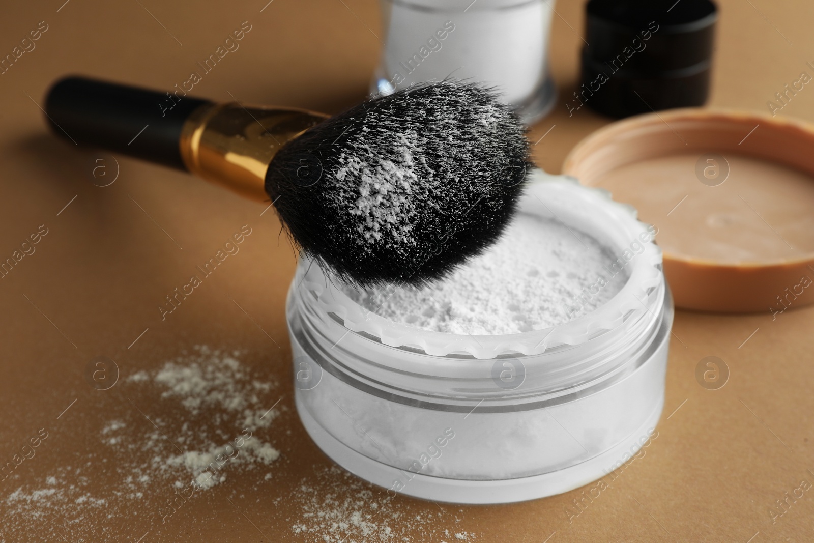 Photo of Makeup brush with rice loose face powder on brown background, closeup