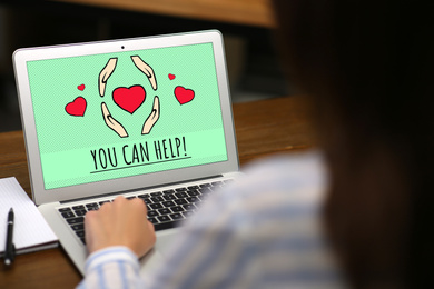 Image of Donations concept. Woman with laptop at wooden table, closeup