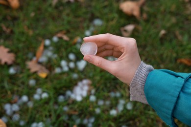 Woman holding hail grain after thunderstorm outdoors, closeup