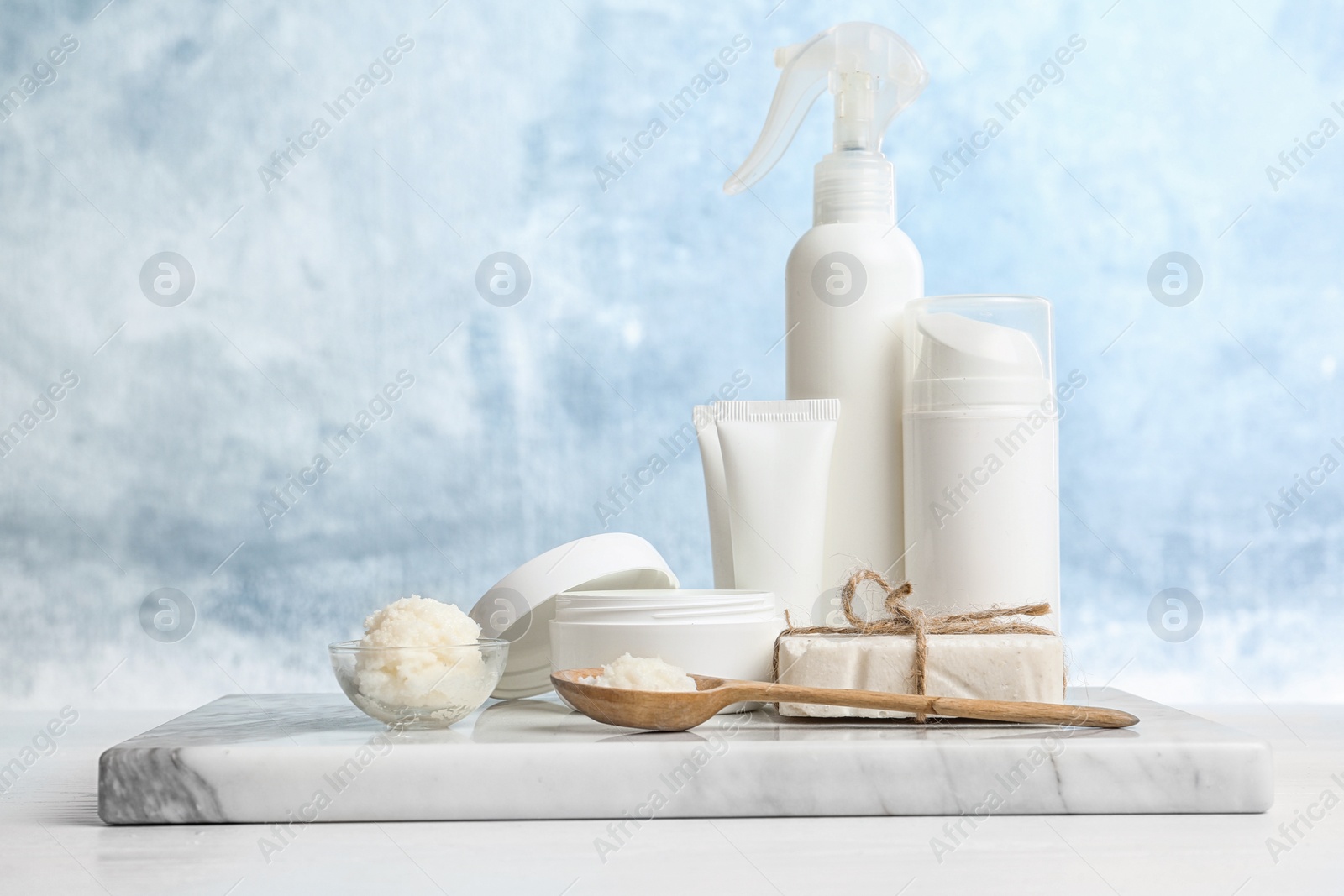 Photo of Board with Shea butter and cosmetic products on table against color background. Space for text