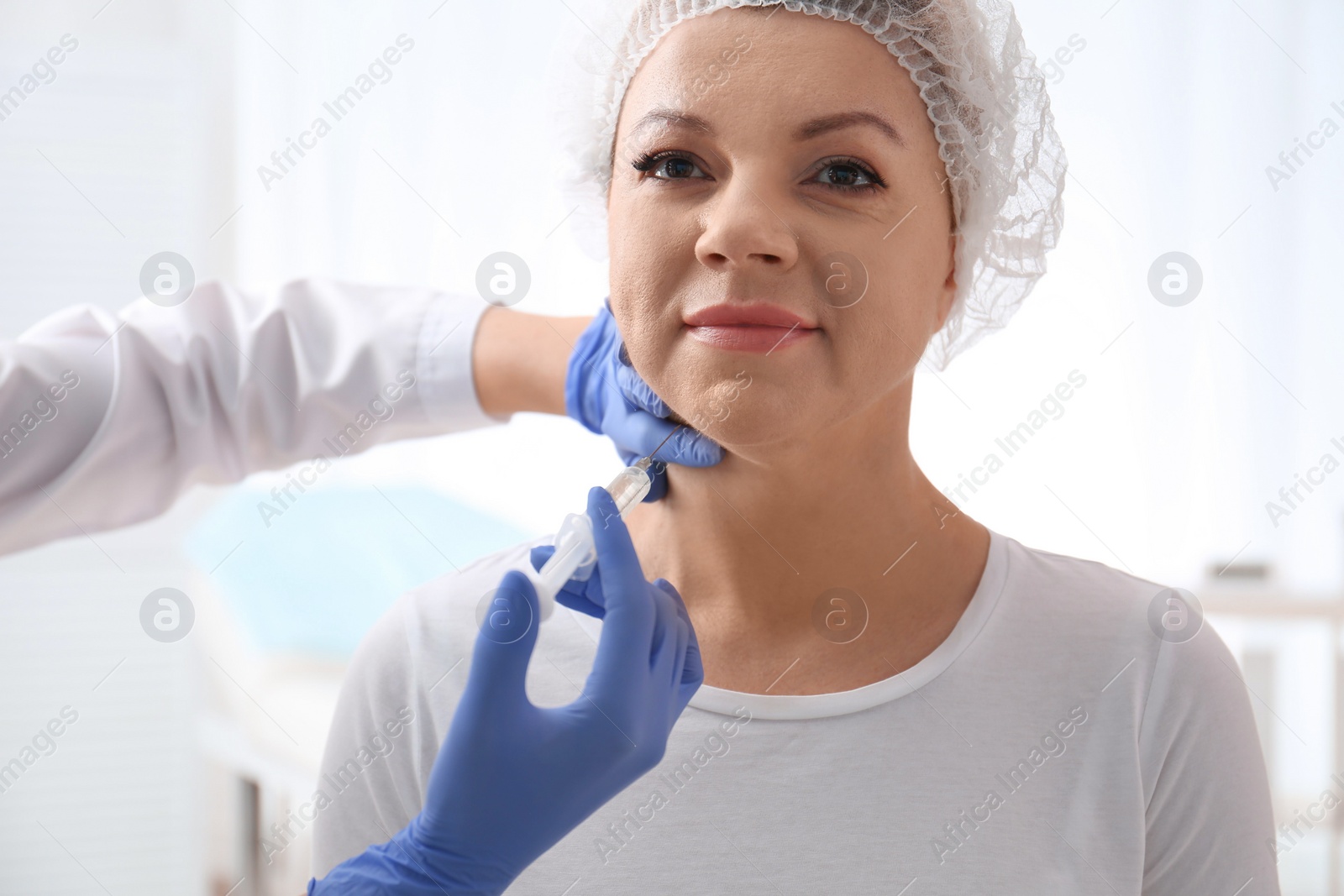 Photo of Mature woman with double chin receiving injection in clinic