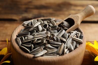 Photo of Raw sunflower seeds in wooden bowl, closeup