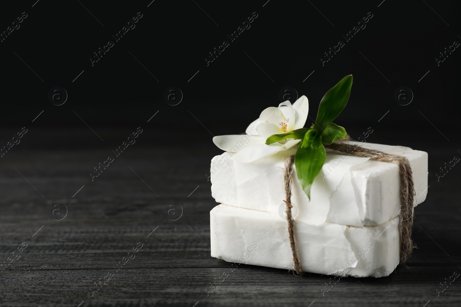 Photo of Handmade soap bars with orchid on table. Space for text
