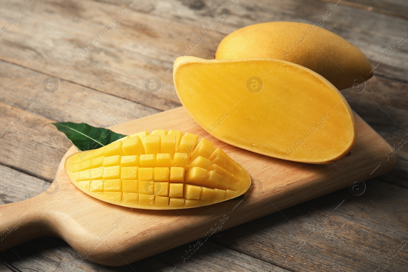 Photo of Ripe fresh mango on wooden board. Tropical fruit