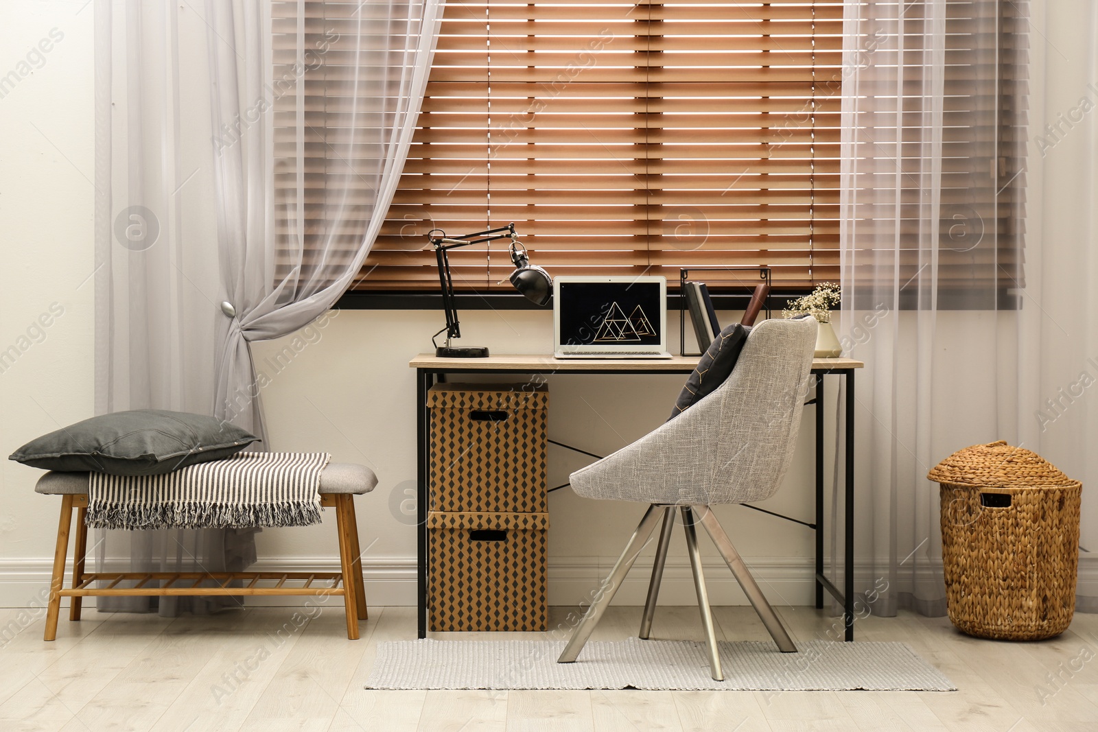 Photo of Comfortable workplace near window with horizontal wooden blinds