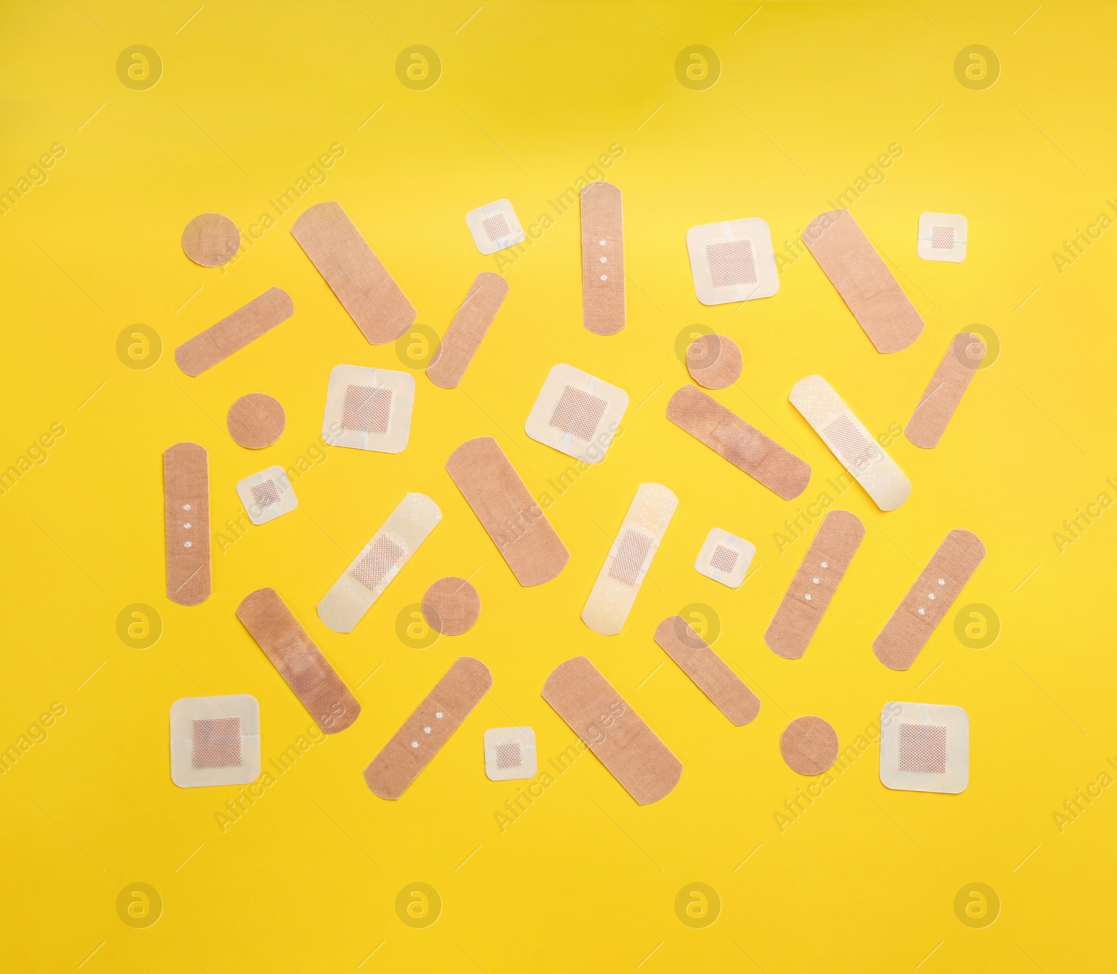 Photo of Different types of sticking plasters on yellow background, flat lay