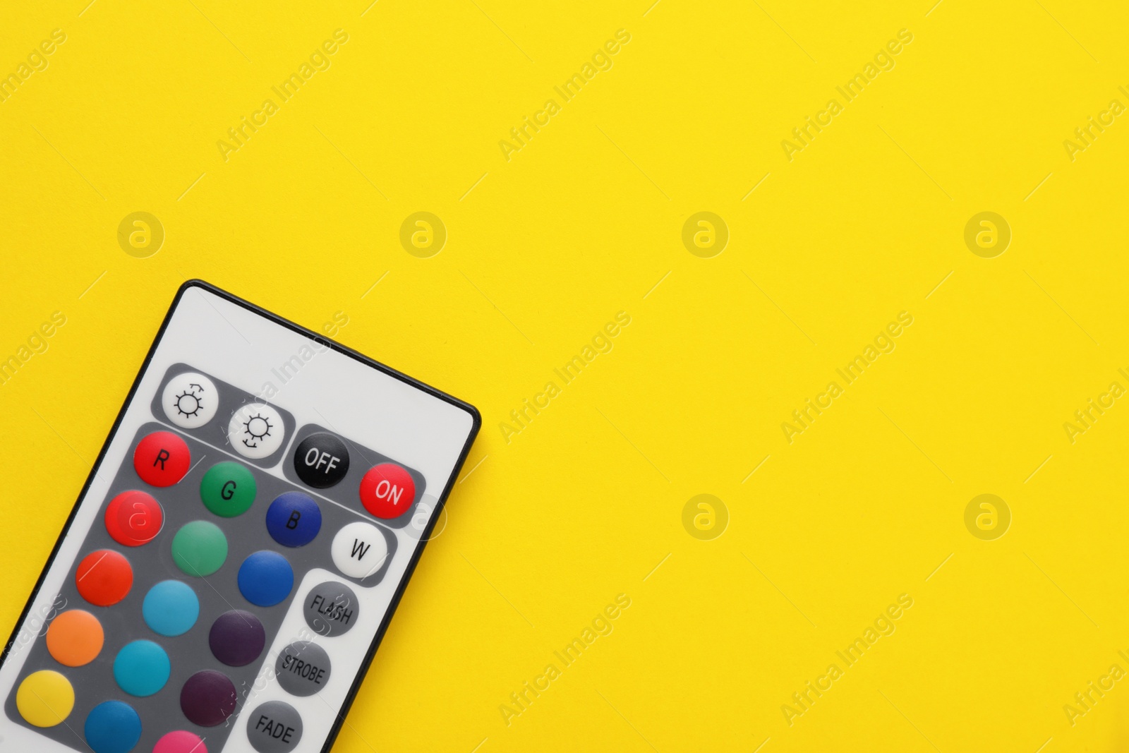 Photo of Remote control on yellow background, top view. Space for text