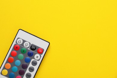 Photo of Remote control on yellow background, top view. Space for text