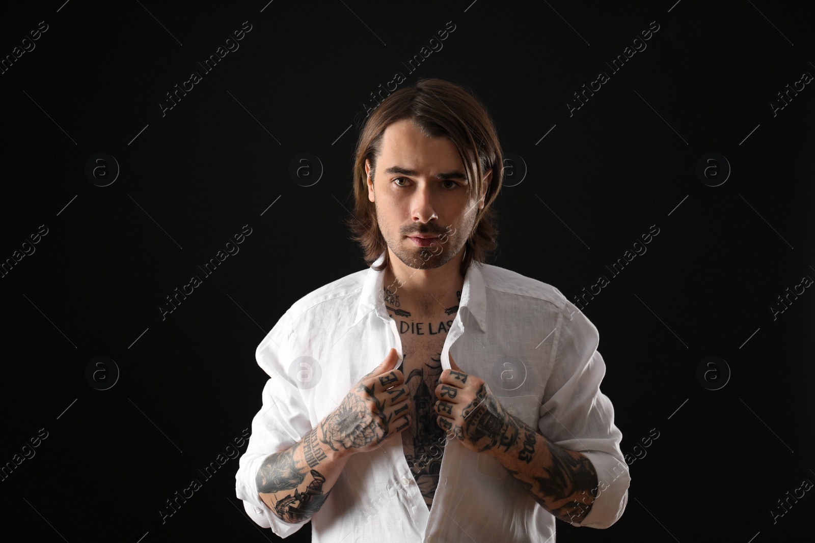 Photo of Young man with tattoos on body against black background