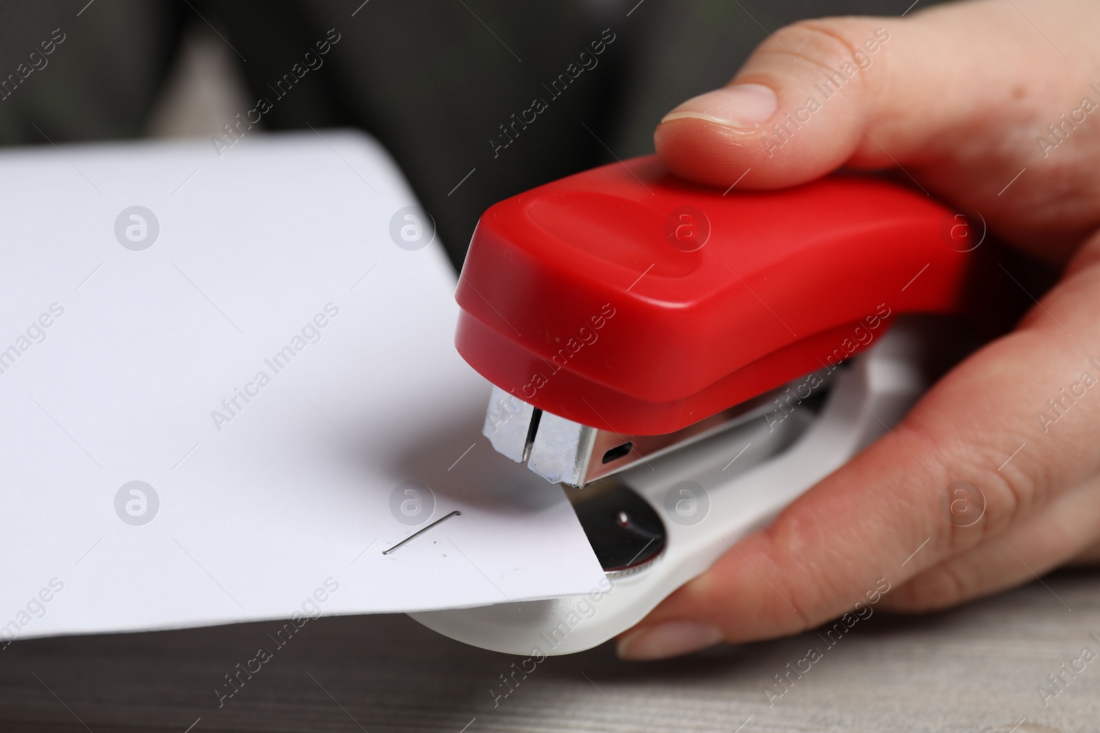 Photo of Woman with papers using stapler at table, closeup