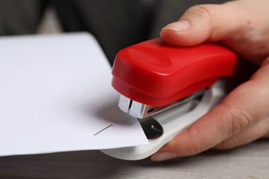 Photo of Woman with papers using stapler at table, closeup