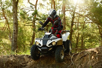 Photo of Man driving modern quad bike in forest. Extreme sport