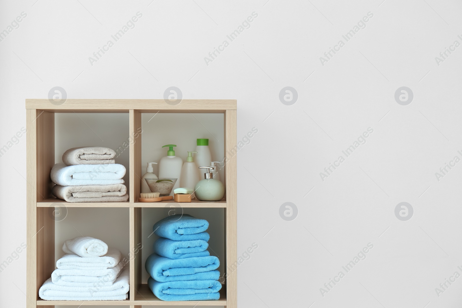 Photo of Clean towels and cosmetics on shelves in bathroom