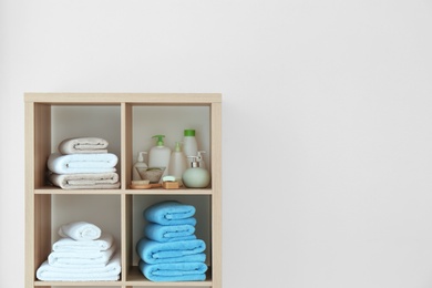 Photo of Clean towels and cosmetics on shelves in bathroom