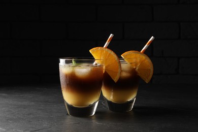 Tasty refreshing drink with coffee and orange juice on grey table against dark background