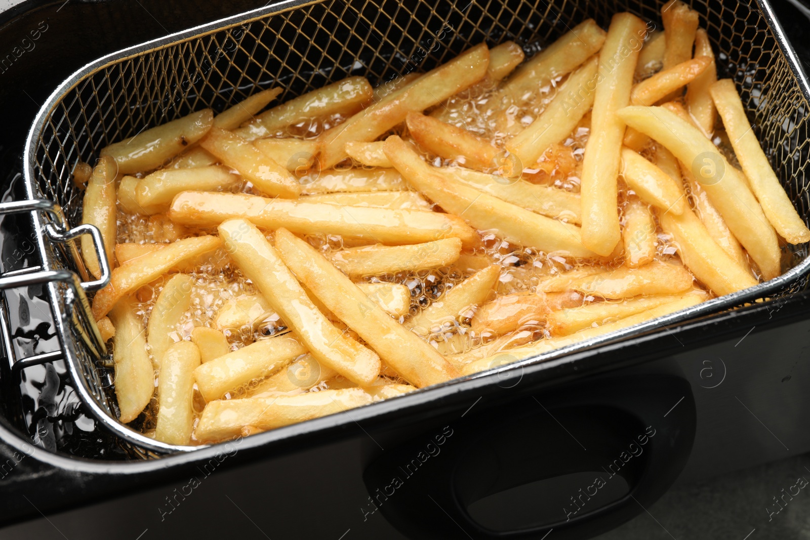 Photo of Cooking delicious french fries in hot oil, closeup