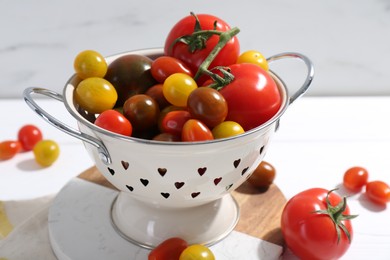 Photo of Metal colander with fresh tomatoes on white table, closeup