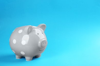 Photo of Grey piggy bank on blue background. Space for text