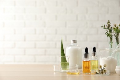 Photo of Organic cosmetic products, natural ingredients and laboratory glassware on wooden table, space for text