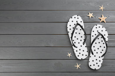 Stylish flip flops and starfishes on grey wooden background, flat lay. Space for text