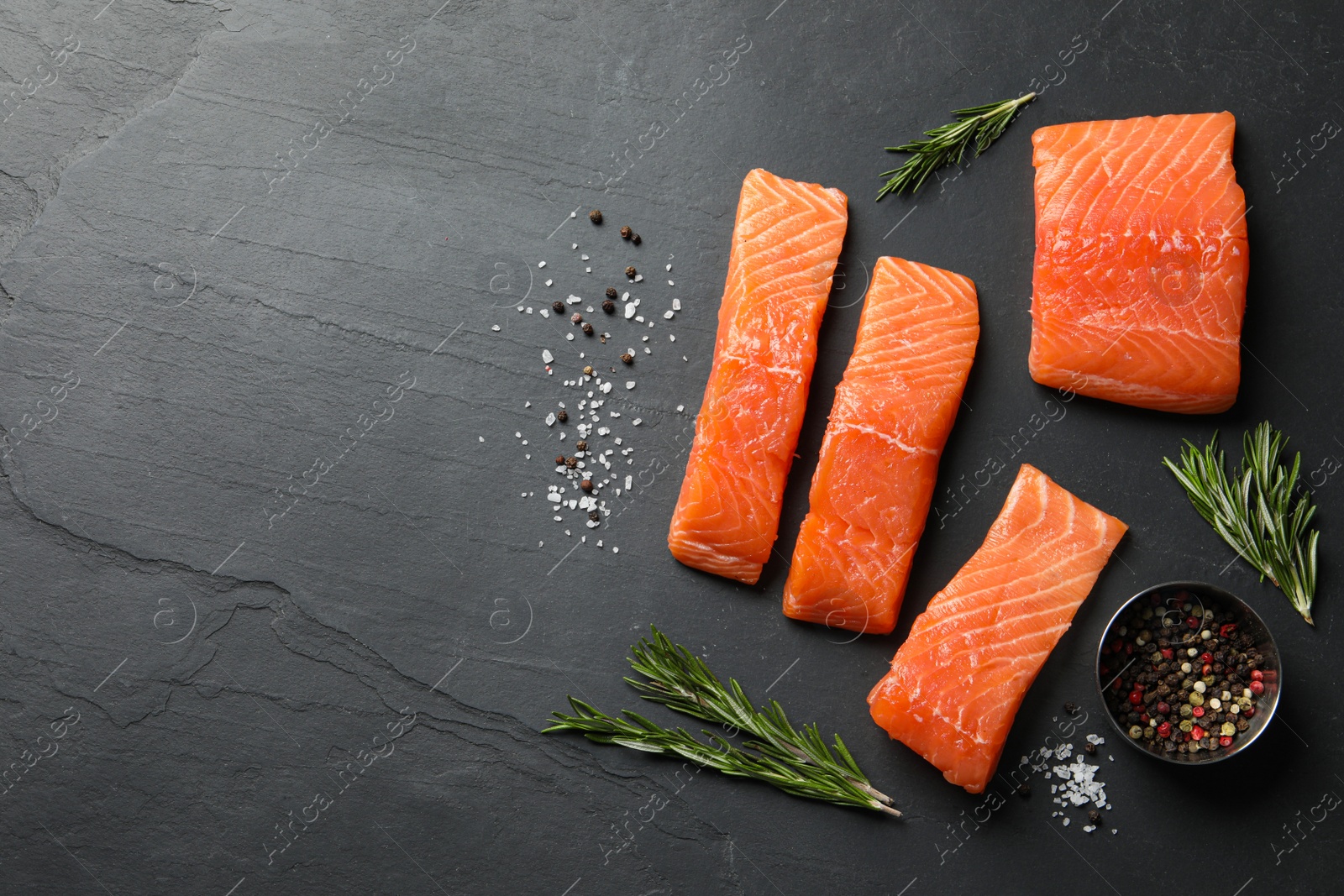 Photo of Fresh raw salmon and spices on black table, flat lay. Space for text