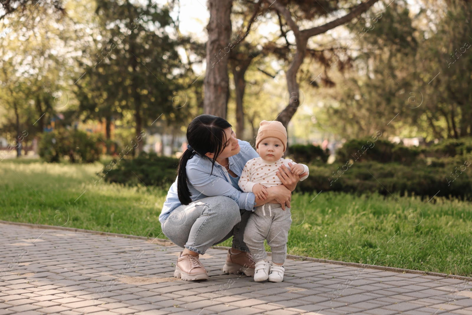 Photo of Mother teaching her baby how to walk outdoors