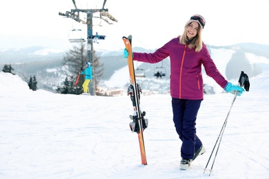 Photo of Young woman with ski equipment spending winter vacation at mountain resort. Space for text