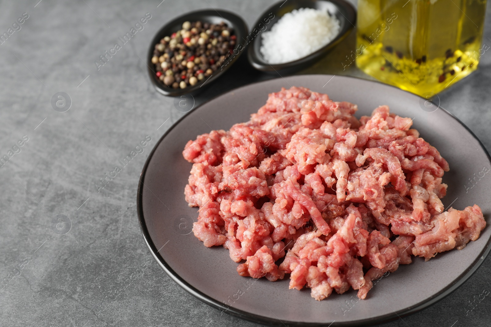 Photo of Raw ground meat, spices and oil on grey table, closeup