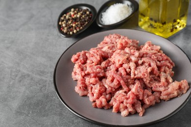 Raw ground meat, spices and oil on grey table, closeup