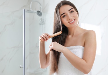 Photo of Beautiful young woman with hair brush in bathroom