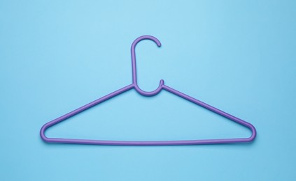 Empty clothes hanger on light blue background, top view