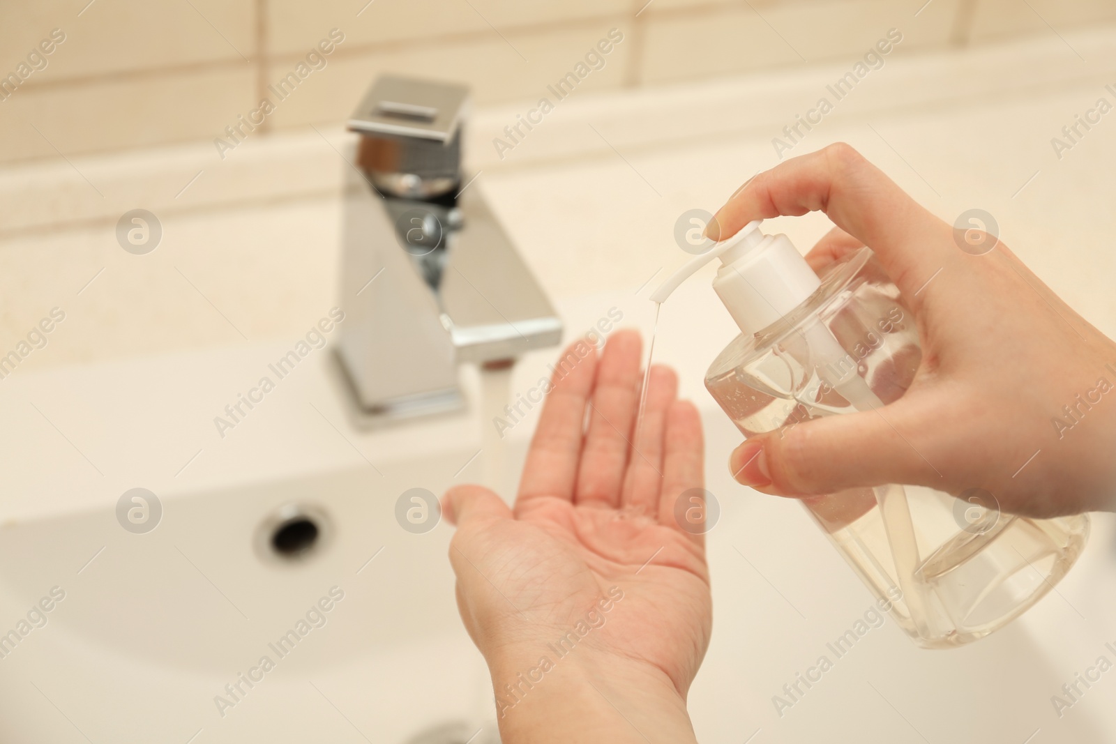 Photo of Woman applying antiseptic soap onto hand in bathroom, closeup. Virus prevention