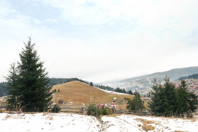 Beautiful winter landscape with buildings and forest on hills