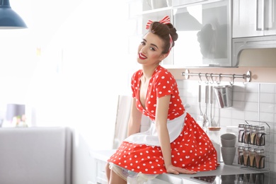 Funny young housewife sitting on kitchen counter