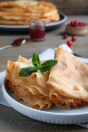 Delicious crepes served with mint on grey wooden table, closeup. Space for text