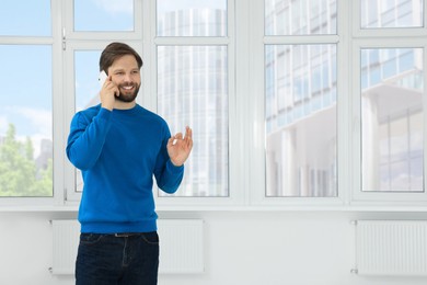 Photo of Man in casual clothes talking on phone indoors, space for text