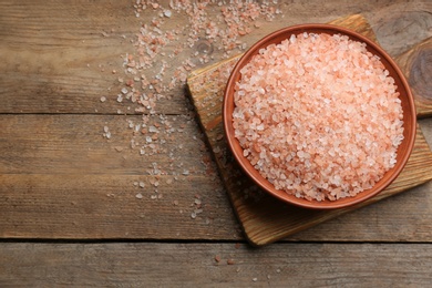 Photo of Pink himalayan salt on wooden table, flat lay. Space for text