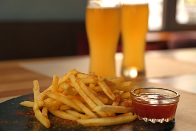 Photo of Delicious hot french fries with red sauce served on table
