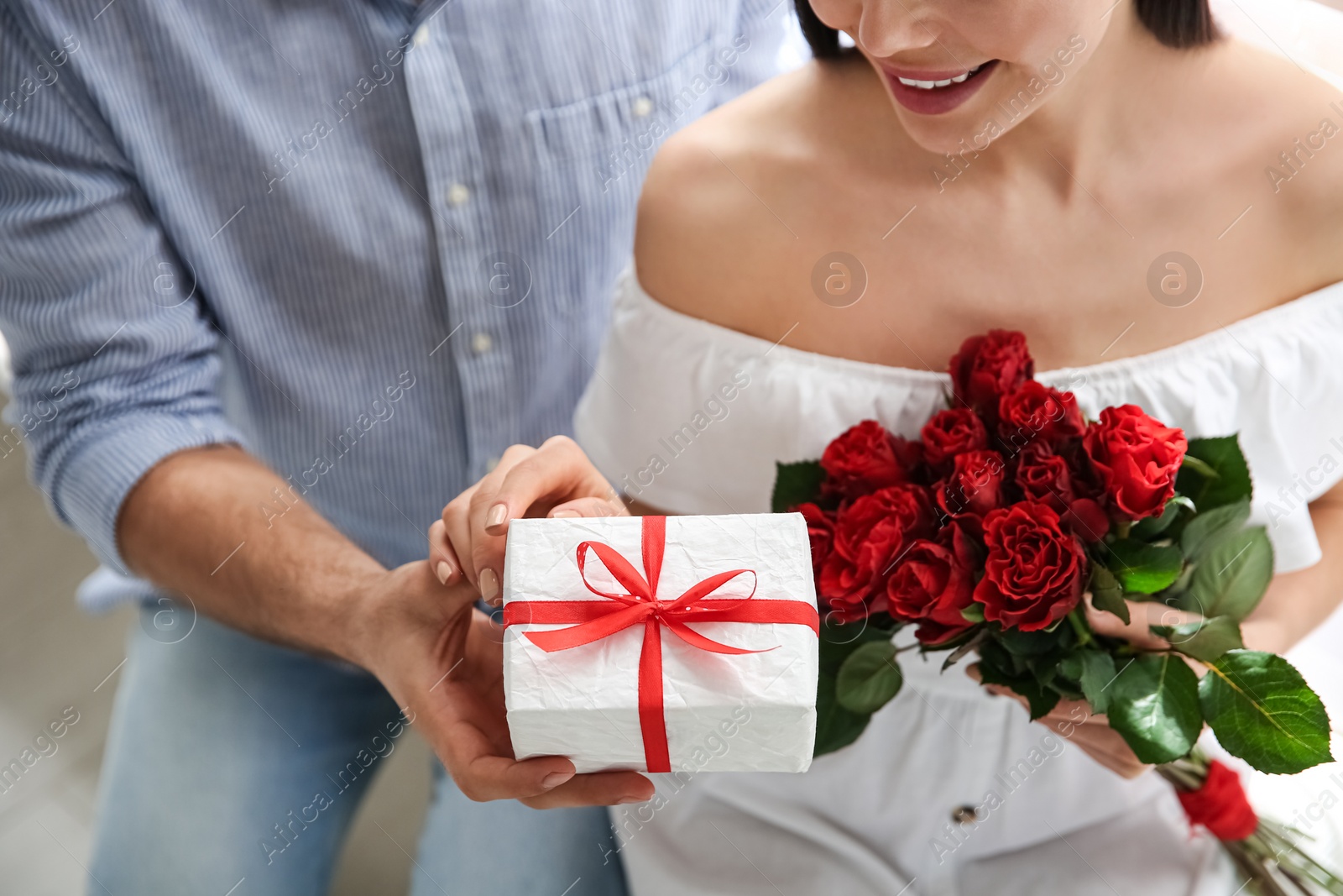 Photo of Man presenting gift to his beloved woman at home, closeup. Valentine's day celebration