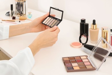 Woman with eyeshadow palette at dressing table, closeup