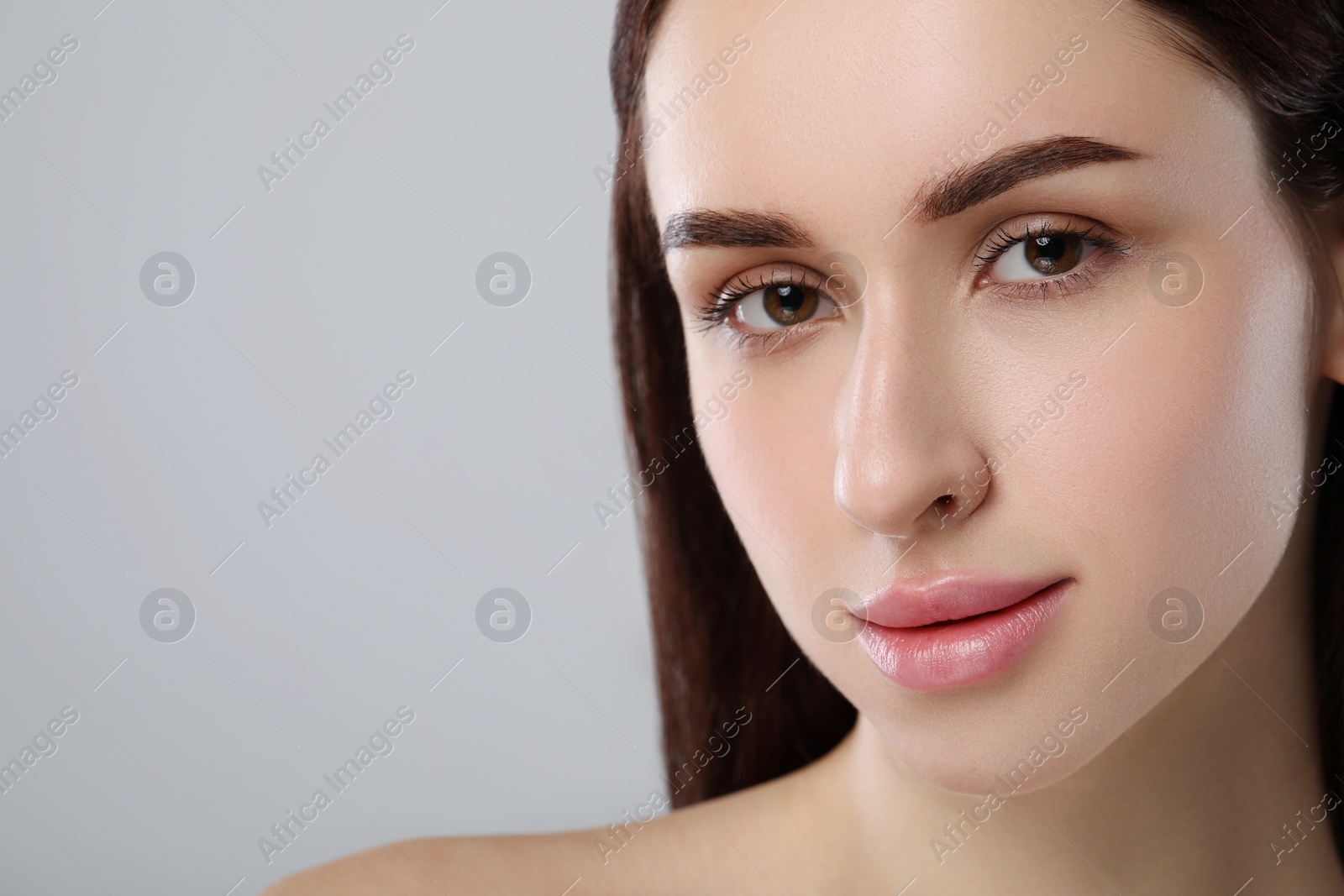 Photo of Beautiful young woman with healthy skin on light grey background, closeup. Space for text