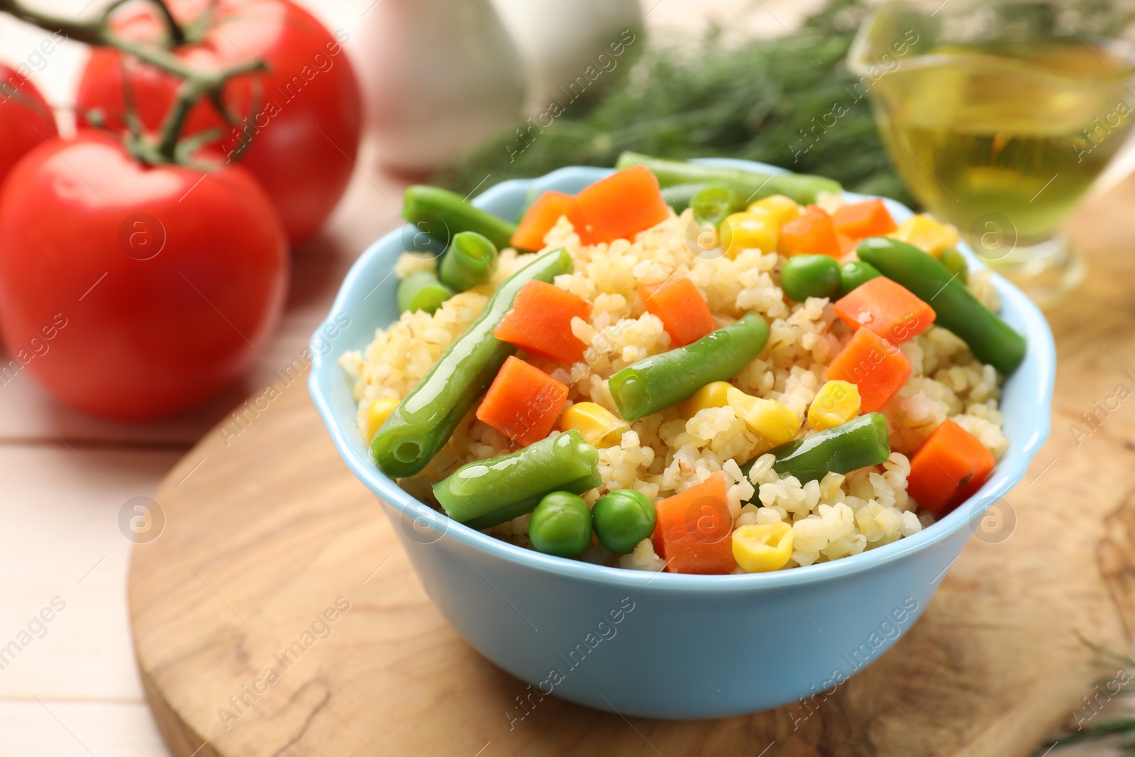 Photo of Delicious bulgur with vegetables in bowl on table, closeup