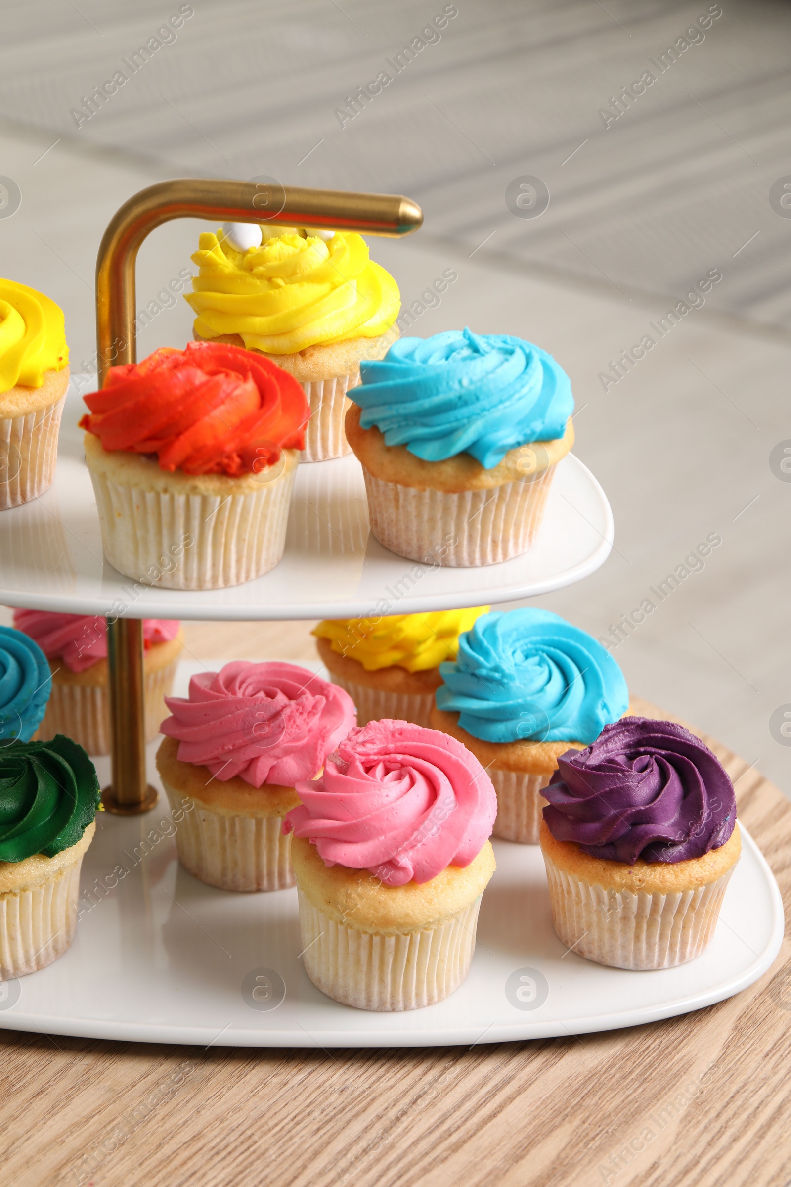 Photo of Delicious cupcakes with bright cream on wooden table indoors, closeup