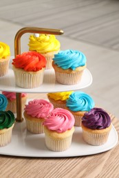 Photo of Delicious cupcakes with bright cream on wooden table indoors, closeup