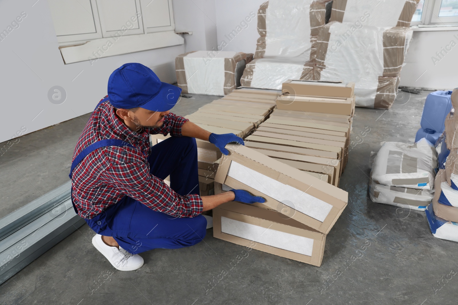 Photo of Construction worker with packed new boxes in room prepared for renovation